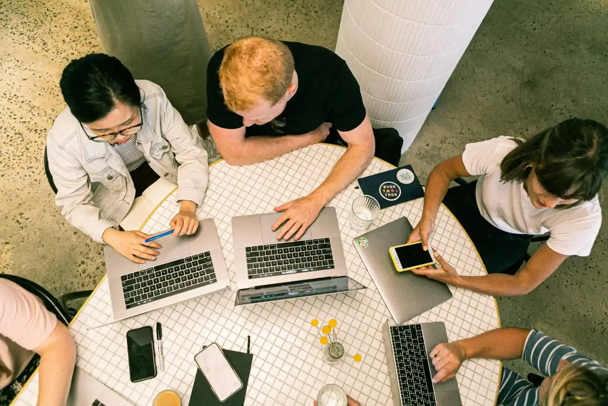 A top-down shot of a team meeting at a table filled with laptops