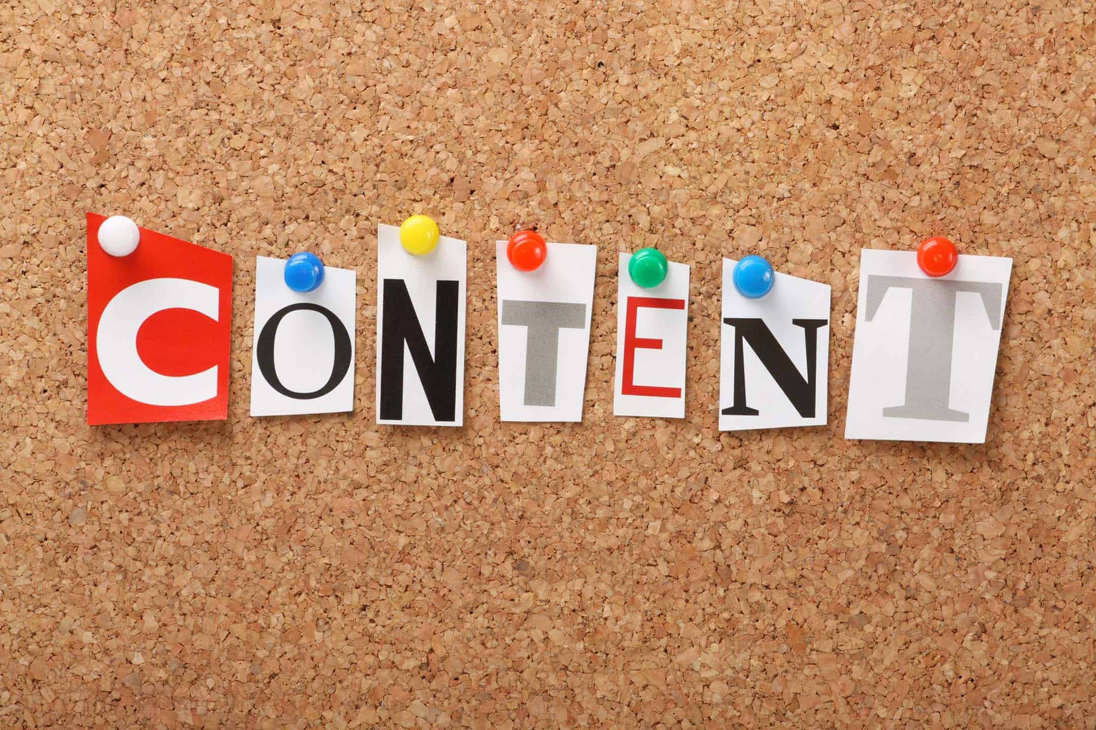 Cut out letters in different fonts pinned to a board spelling the word Content